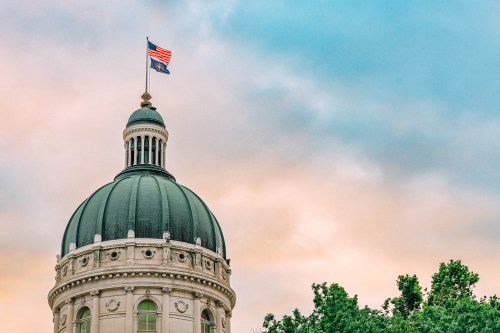 USA and Indiana Flag atop the State Capitol building in Indianapolis, Indiana at Sunset